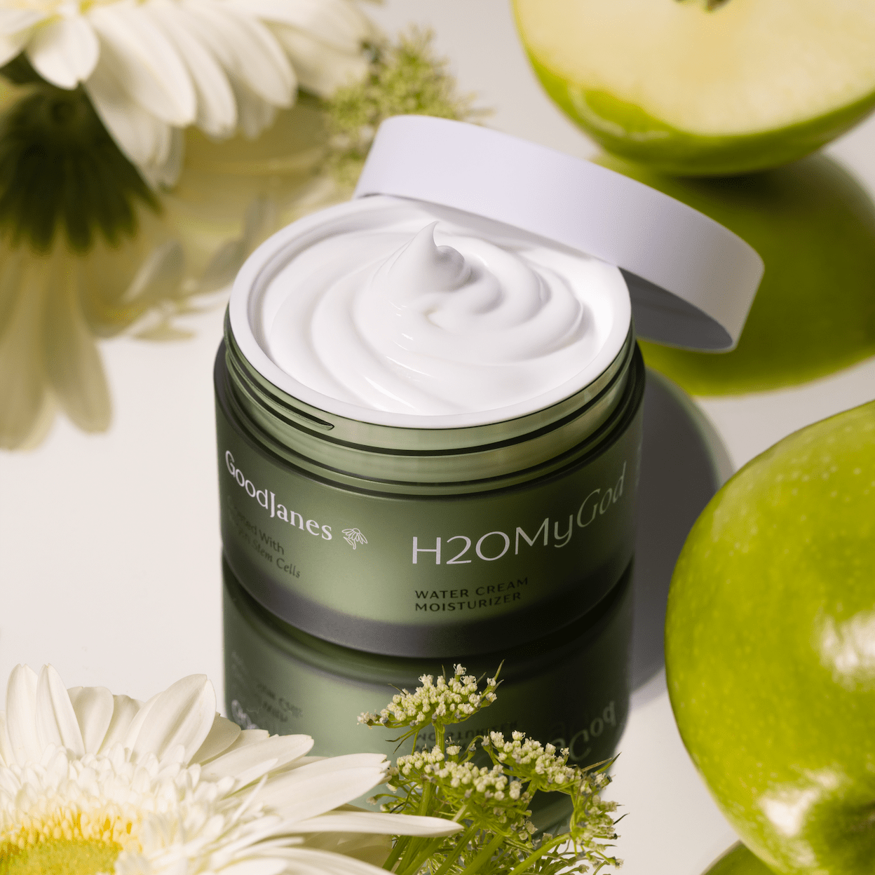 Jar of H2O My Gold cream with green apples and white flowers on a light background
