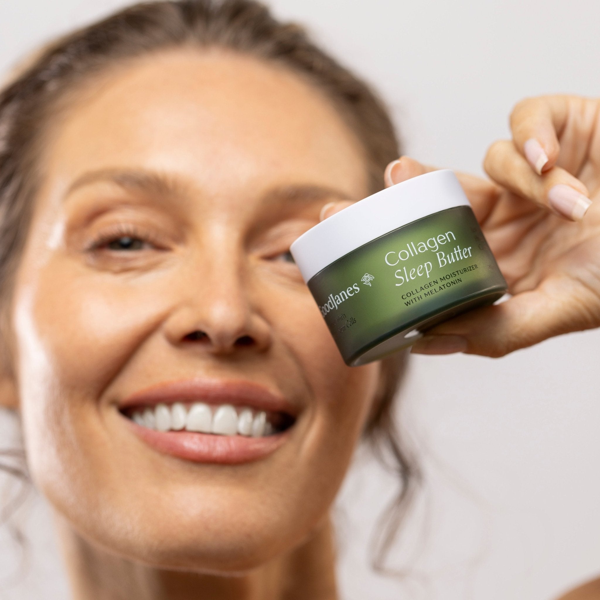 Woman holding a jar of Collagen Sleep Butter against a plain background