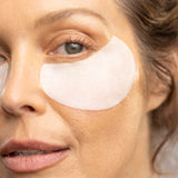 Close-up of a woman's face with eye patches, focusing on skincare.