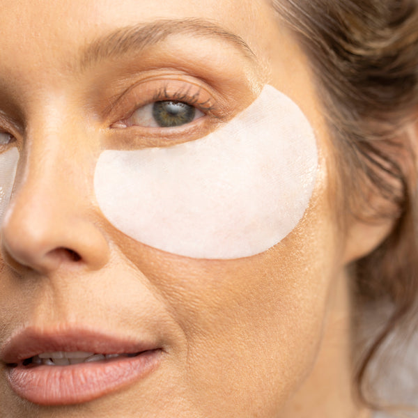 Close-up of a woman's face with eye patches, focusing on skincare.